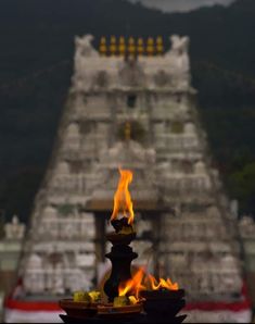 flames are lit in front of a temple