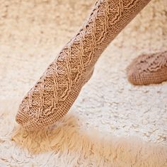 a woman's legs and feet in knitted socks on carpeted flooring