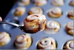 a person holding a spoon full of cinnamon rolls