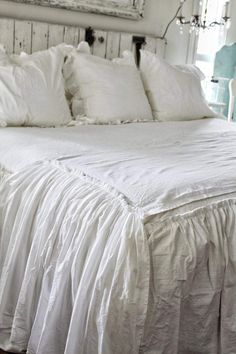 a bed with white sheets and pillows in a room