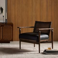 a black chair sitting on top of a rug next to a wooden cabinet and sideboard