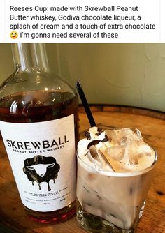 a bottle of skrewball and a glass filled with ice sits on a wooden table