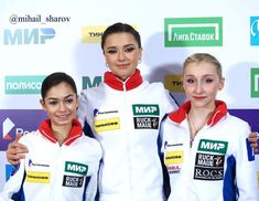 three women standing next to each other in front of a white and blue wall with logos on it