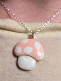 a woman wearing a pink and white mushroom pendant on a silver chain with polka dots