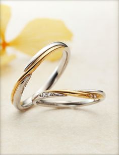 two gold and silver wedding rings with diamond accents on the side, sitting next to each other