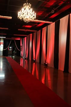 a red carpeted hall with chandelier and curtains