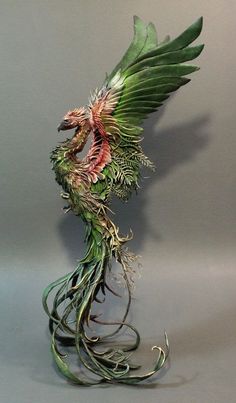 a green and red dragon statue with its wings spread out, on a gray background