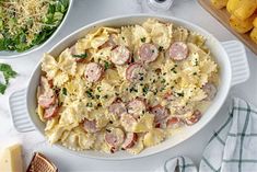 a bowl of pasta with sausage and parmesan cheese next to other food items