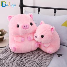 two pink stuffed animals sitting on top of a bed next to each other in front of a pillow