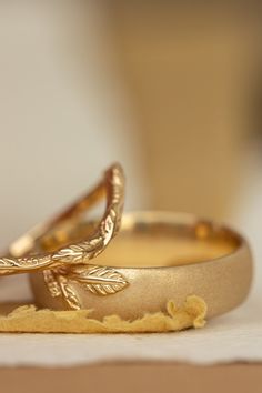 two gold wedding rings sitting on top of a piece of paper next to each other