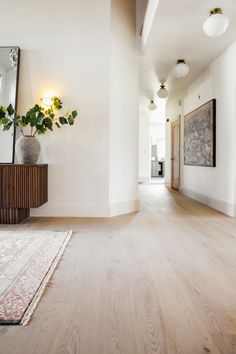 an empty room with wood flooring and white walls in the background is a large mirror on the wall