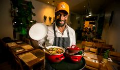 a man in an orange hat holding two pots and pans