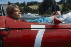 a woman sitting in the driver's seat of a red race car