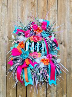 a colorful wreath is hanging on a wooden fence