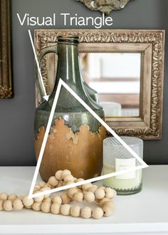 a vase sitting on top of a white table next to a mirror and some nuts