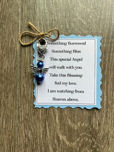 a card with an angel charm attached to it on a wooden table next to a string