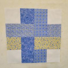 a blue and yellow patchwork quilt on a white wall with holes in the middle