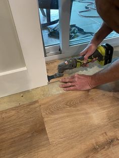 a man is using a drill to install a door handle on a wood paneled floor