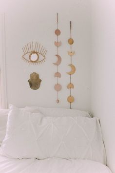 a white bed topped with pillows next to a wall mounted sun and moon decorations on the wall