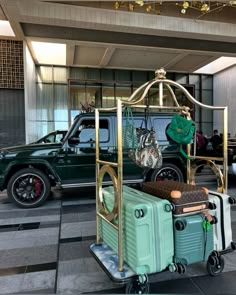 a green truck parked in front of a building with luggage on it's wheels