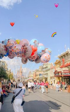 people are walking down the street with many balloons in the shape of animals and hearts