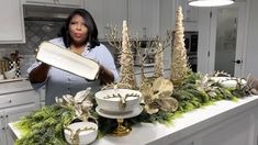 a woman holding up a tray with christmas decorations on top of it in a kitchen