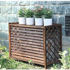 three potted plants sitting on top of a wooden planter in front of a brick wall