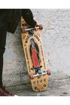 a person standing next to a wall with a skateboard on their feet and one hand holding the board