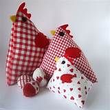 two red and white stuffed chickens sitting next to each other on a white tablecloth