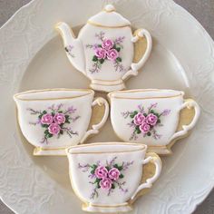 four decorated tea cups and saucers on a white plate with gold trimmings