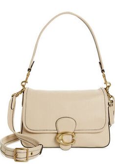 a white handbag with a gold ring on the front and strap around the shoulder