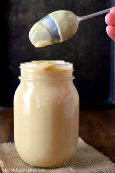 a spoon full of peanut butter on top of a jar