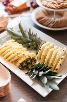 pineapple slices and other fruit on a plate at a table with plates of food in the background