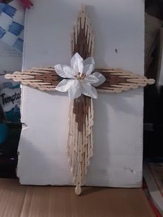 a wooden cross decorated with white flowers on top of a cardboard box in the shape of a crucifix