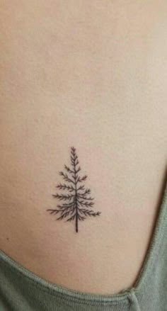 a small pine tree tattoo on the back of a woman's stomach