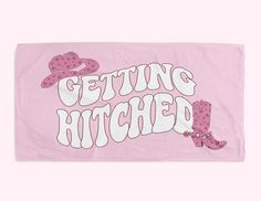 a pink towel with the words getting hitched written in white letters and cowboy boots