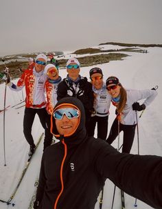 a group of people standing on top of a snow covered slope wearing skis and goggles