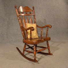 a wooden rocking chair with a pillow on it's back and armrests