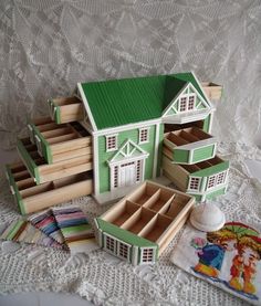 a green and white doll house surrounded by other wooden toys