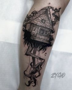 a woman's leg with a house tattoo on it