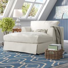 a white chaise lounge chair sitting on top of a blue rug next to a window