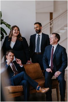 a group of people standing and sitting around each other in business attire smiling at the camera