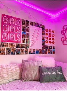 a bedroom with pink lights and pictures on the wall above it, along with pillows