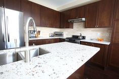 a kitchen with marble counter tops and stainless steel appliances in the center, along with dark wood cabinets