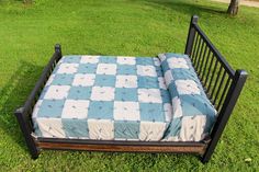 a bed frame with a blue and white checkered blanket on it in the grass