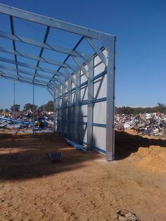 a large metal structure sitting on top of a dirt field