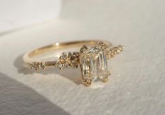 an engagement ring with a large diamond surrounded by smaller diamonds on top of white paper