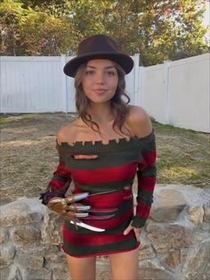 a woman in a dress and hat posing for the camera with scissors on her arm