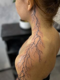 the back of a woman's neck with a lightning tattoo on her left side