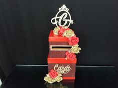 the cake is decorated with red and gold flowers on it's sides, which are adorned with a tiara